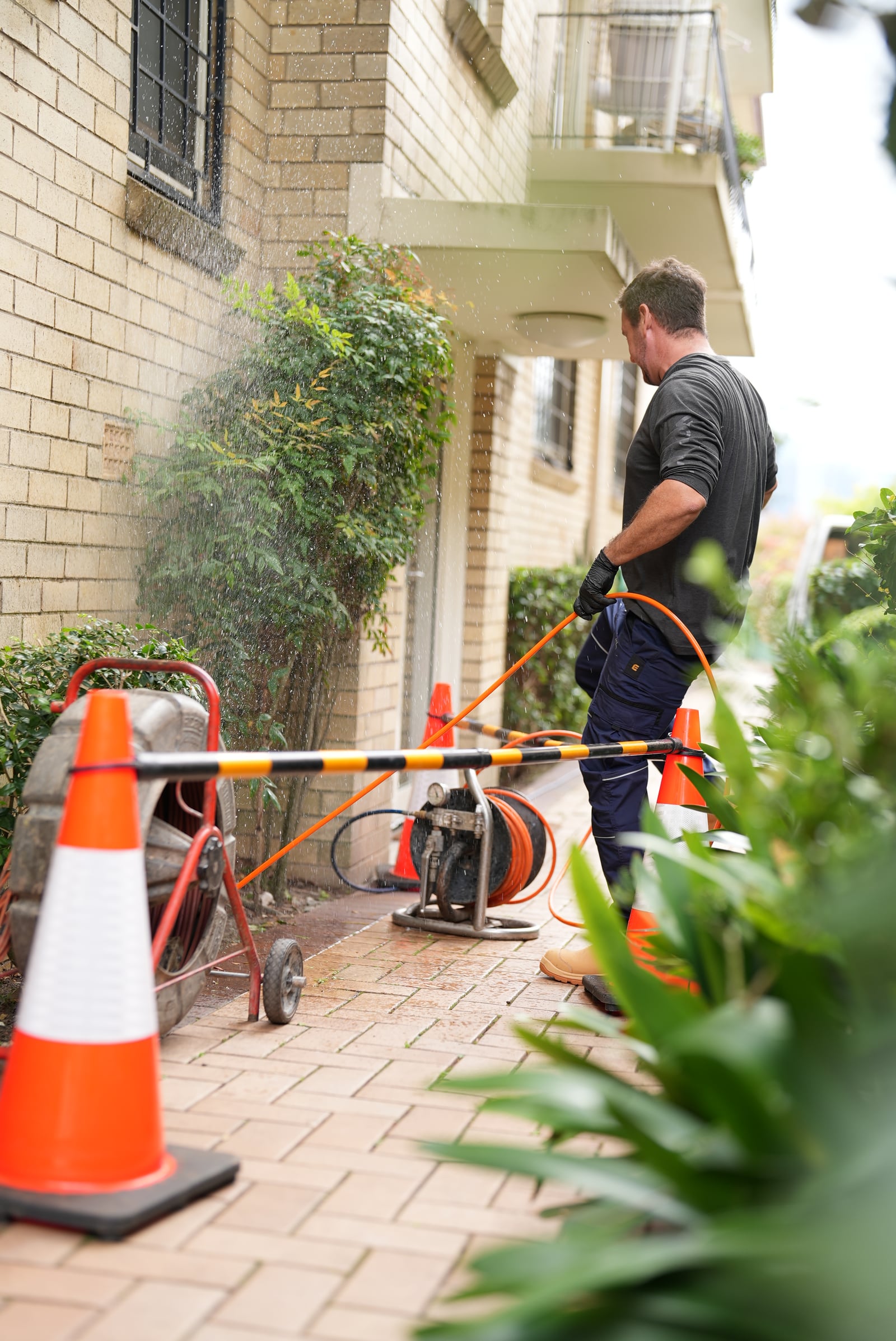 Drainr technician on site with drain clearing equipment and safety cones at a Sydney blocked drain job