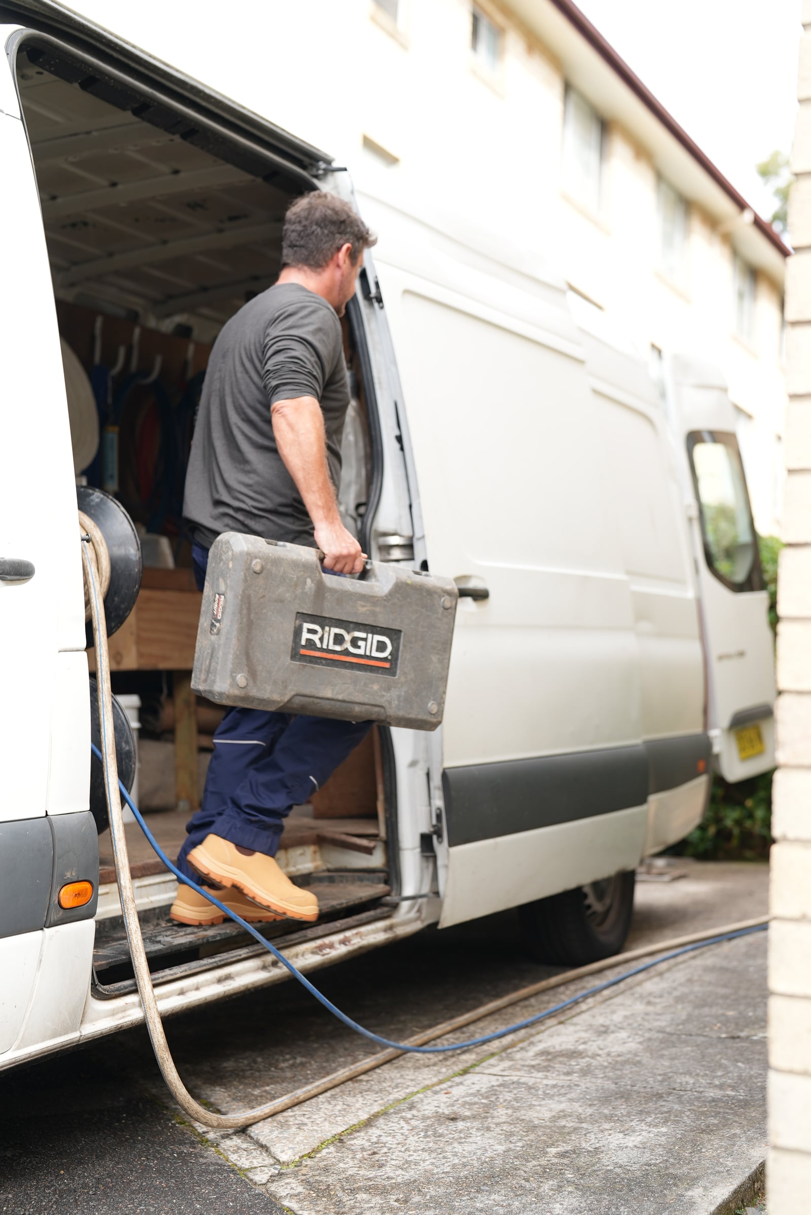 Drainr technician unloading RIDGID drain equipment from the service van at a Sydney job